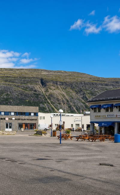 Town-square shops beneath a bare Finnmark mountain in Lakselv, northern Norway.