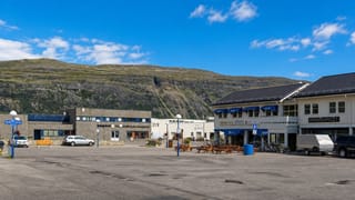 Town-square shops beneath a bare Finnmark mountain in Lakselv, northern Norway.