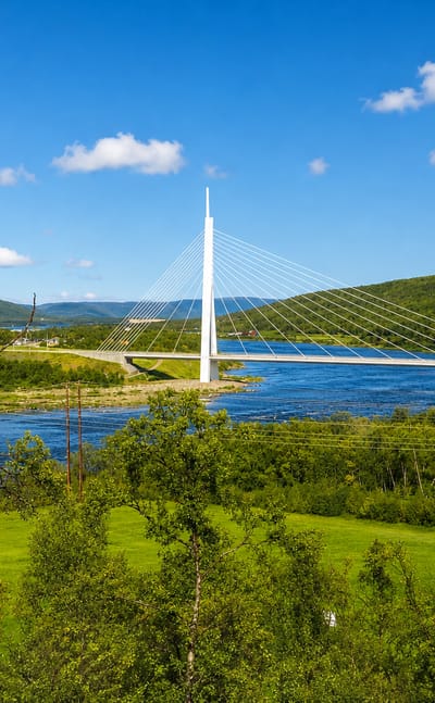 White cable-stayed bridge spanning the Tana River amid green hills at Tana Bru, Finnmark, Norway