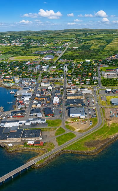 Aerial view of Vadso on its harbor peninsula with the Vadsoya bridge and Finnmark hills, Norway.