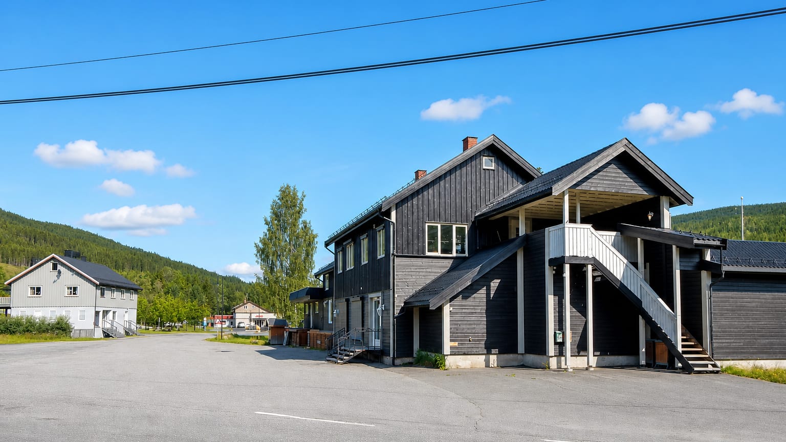 A dark timber building and quiet street in the village of Bruflat, Innlandet, Norway, under clear skies.