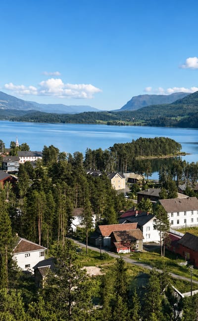 Fagernes, Norway, a lakeside town of traditional houses and a white church by Strondafjorden, ringed by forested mountains
