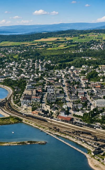 Aerial view of Hamar, Norway, the lakeside town and its waterfront railway yards along Lake Mjøsa under a blue sky