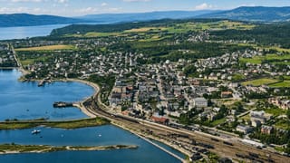 Aerial view of Hamar, Norway, the lakeside town and its waterfront railway yards along Lake Mjøsa under a blue sky