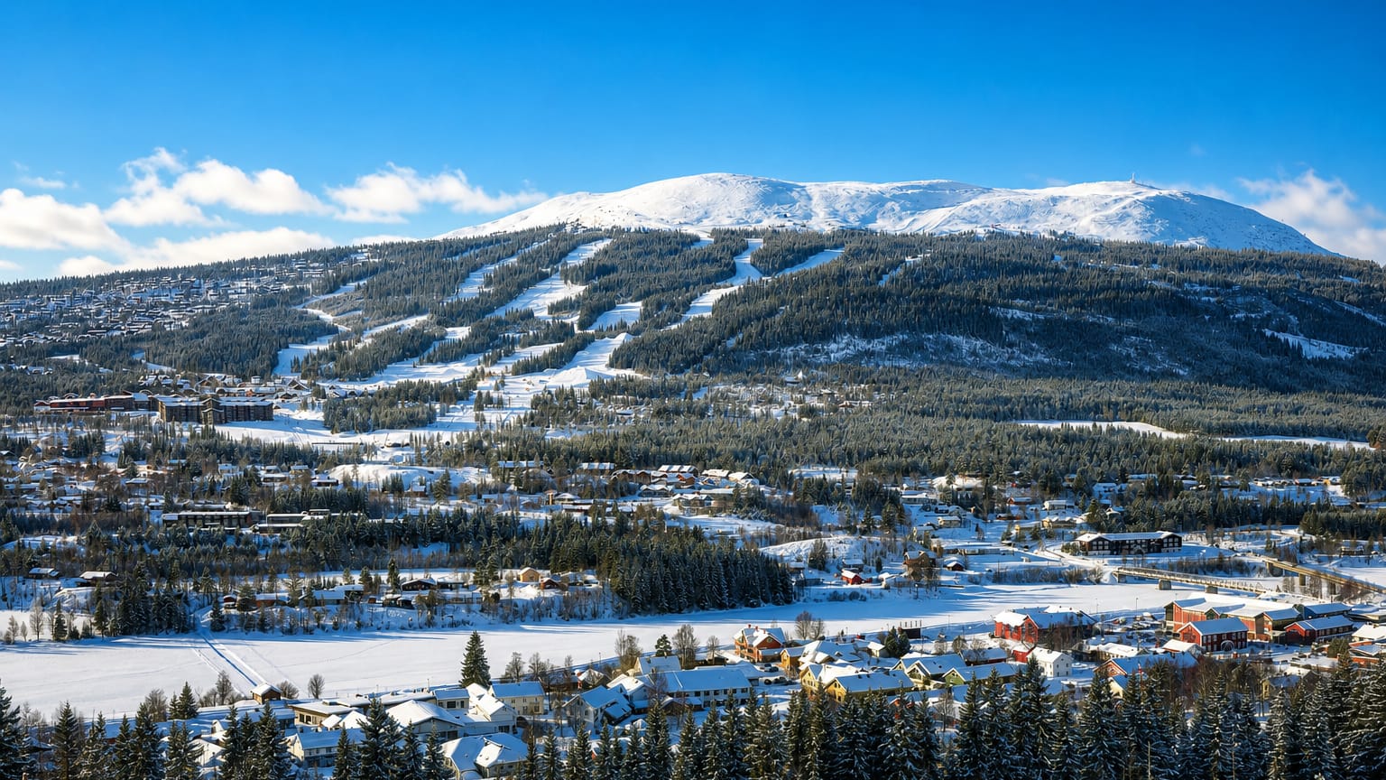 Snow-covered Innbygda in Trysil below the forested ski slopes of Trysilfjellet under a bright winter sky, Norway.