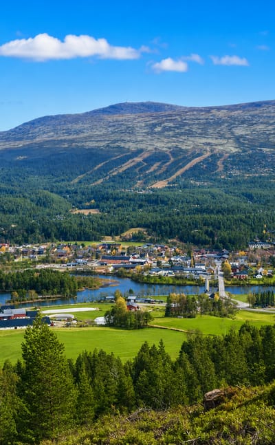 Valley view of Os, Norway, with a village by a lake, green fields and a ski-marked mountain behind