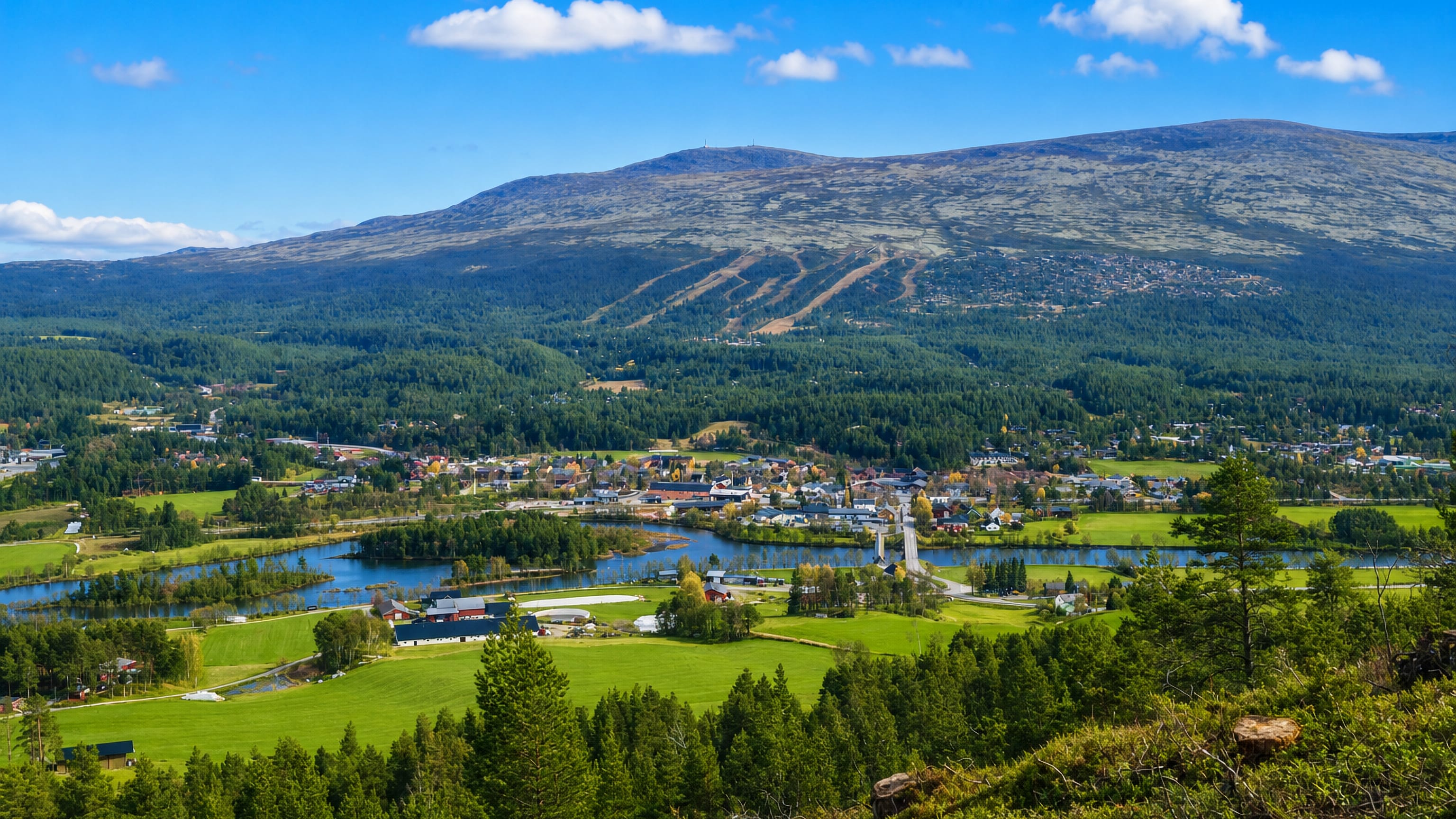 Valley view of Os, Norway, with a village by a lake, green fields and a ski-marked mountain behind