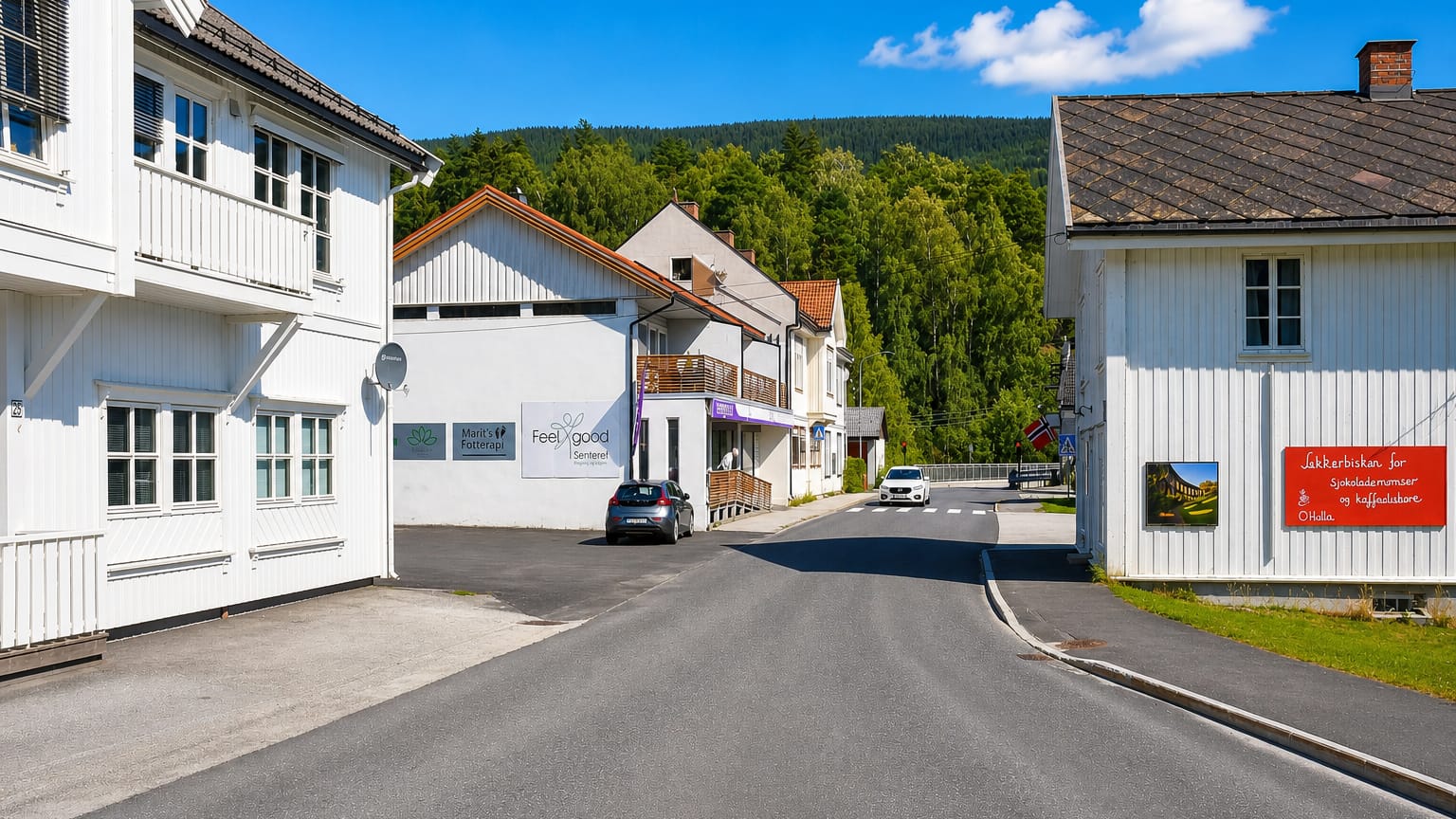 White timber houses and shop signs along a village street with a Norwegian flag in Ringebu, Norway