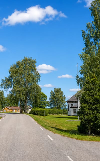 A village road passing the white spired church at Sand in Nord-Odal, Innlandet, Norway.