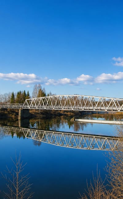 Steel truss bridge mirrored in the calm Glomma river at Skarnes, Norway, in early spring