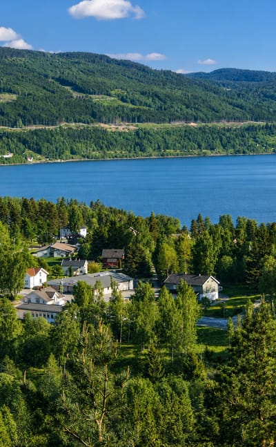 Lakeside village with a white church and old brick works among forest near Stange, Innlandet, Norway