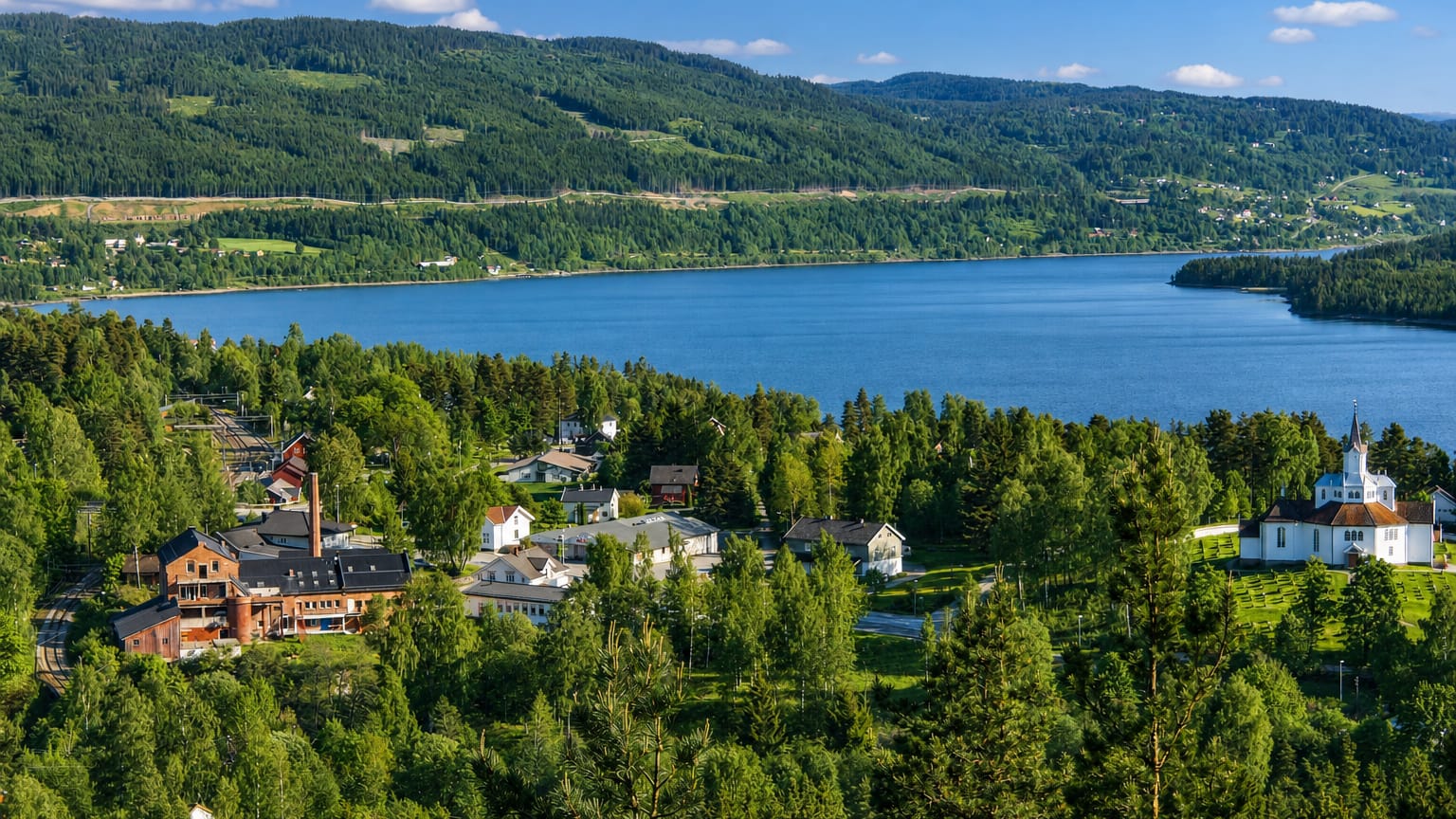 Lakeside village with a white church and old brick works among forest near Stange, Innlandet, Norway