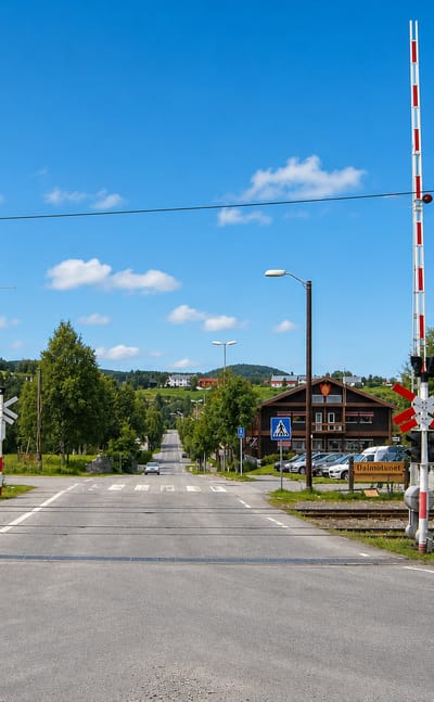 Railway level crossing on the main street of Tolga with road signs toward Drevsjo