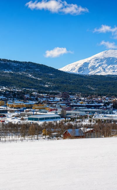 Winter view of Tynset, Norway, spread below a snow-capped mountain under a clear blue sky
