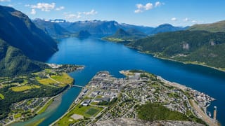 Aerial of Andalsnes on the Rauma river delta where it meets Romsdalsfjord, ringed by jagged snow-capped peaks