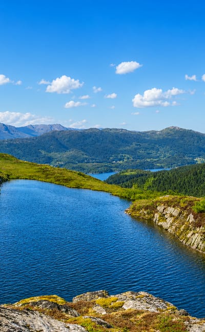 A mountain lake and fjord landscape with distant peaks near Aure, Møre og Romsdal, Norway.
