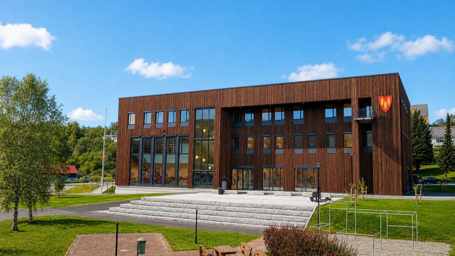 A modern timber-clad municipal building with a plaza and steps in Bruhagen, Norway.