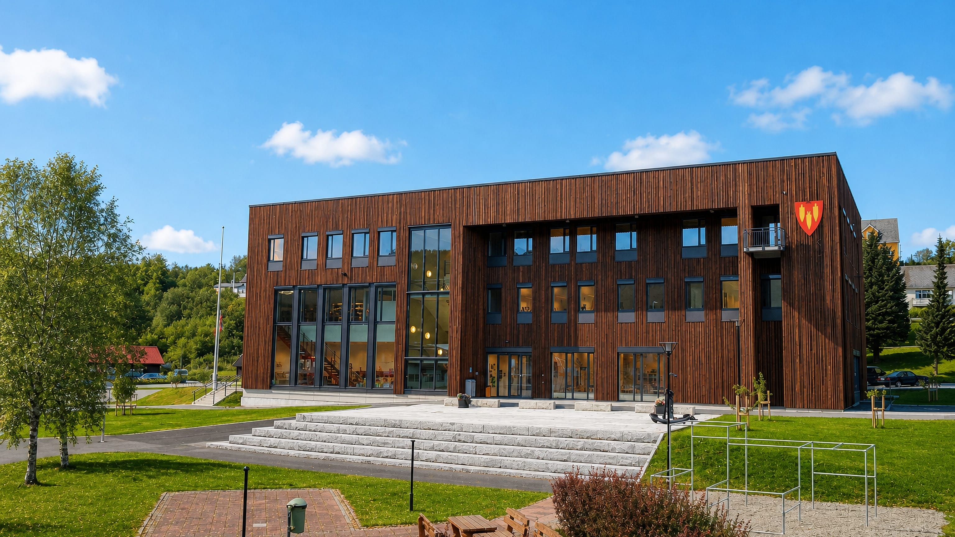 A modern timber-clad municipal building with a plaza and steps in Bruhagen, Norway.