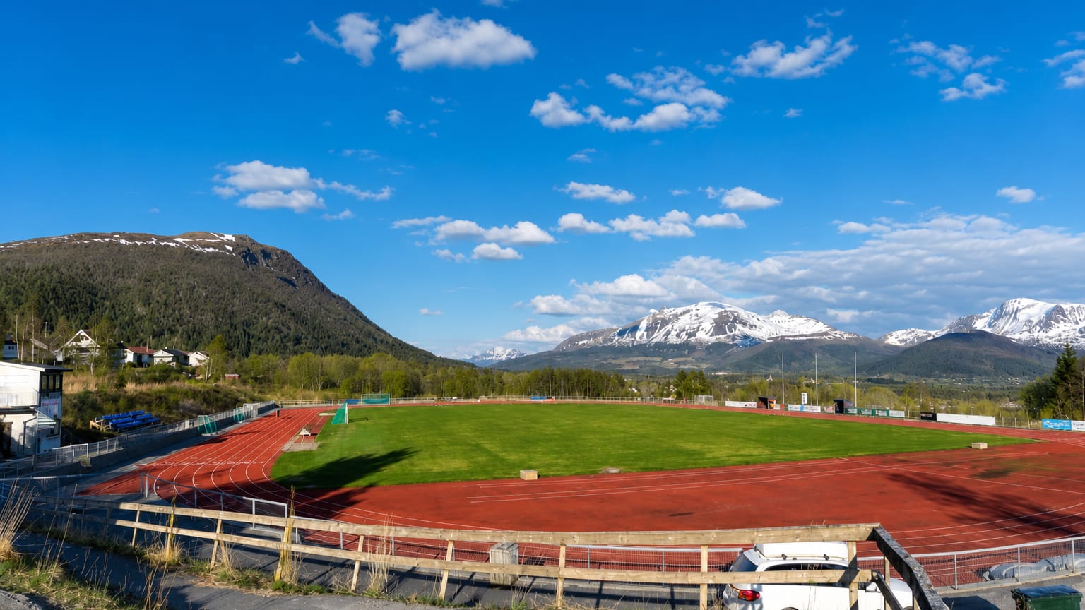 Athletics track and football pitch below snow-capped mountains on the edge of Elnesvågen, Norway.