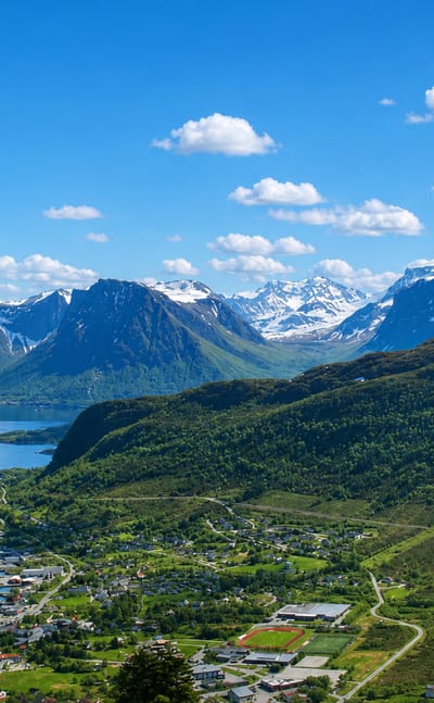 The coastal town of Hareid beside its fjord with snow-capped Sunnmøre mountains rising behind, Norway.