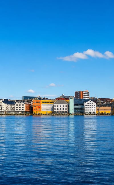 Row of colourful waterfront buildings lining Kristiansund's harbour across calm blue water