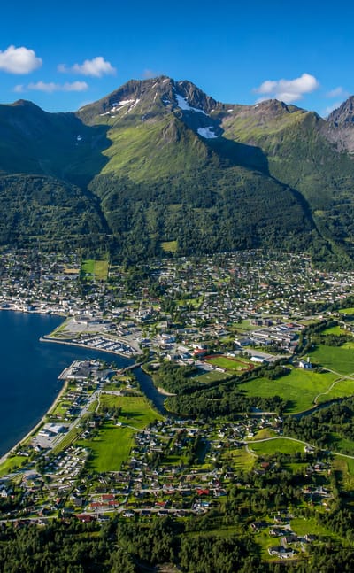 Aerial view of Ørsta, Norway, spread along its fjord shore beneath the steep green Sunnmøre mountains