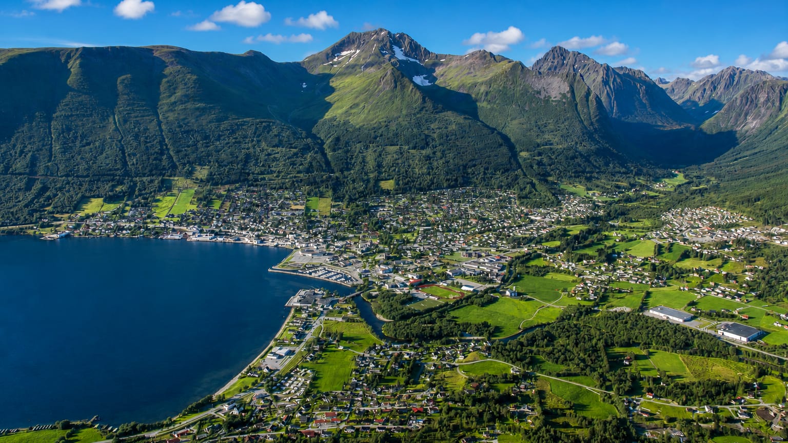 Aerial view of Ørsta, Norway, spread along its fjord shore beneath the steep green Sunnmøre mountains