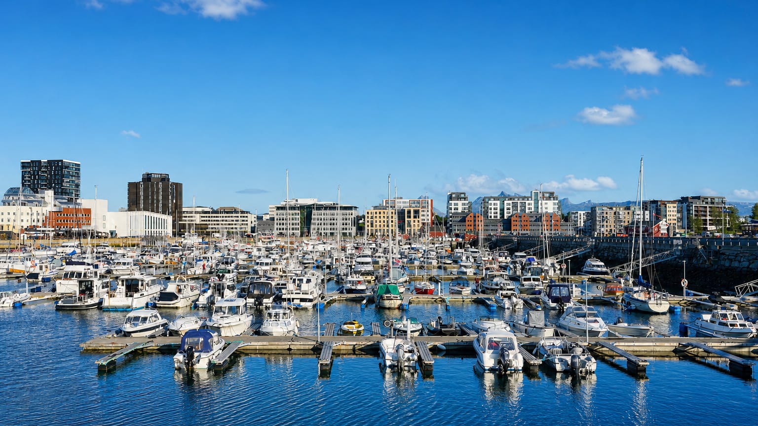 Bodo marina full of boats with the modern waterfront and distant mountains behind