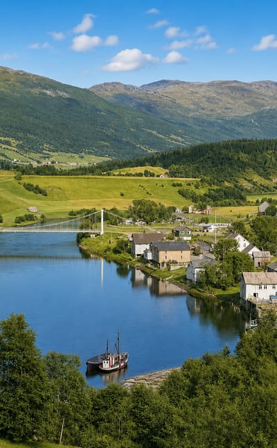 Korgen village along a river in a green Nordland valley, with a white church, a cable bridge and forested mountains.