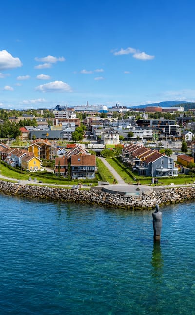 Mo i Rana waterfront with the Havmannen granite sculpture standing in the Ranfjord below the town and forested hills