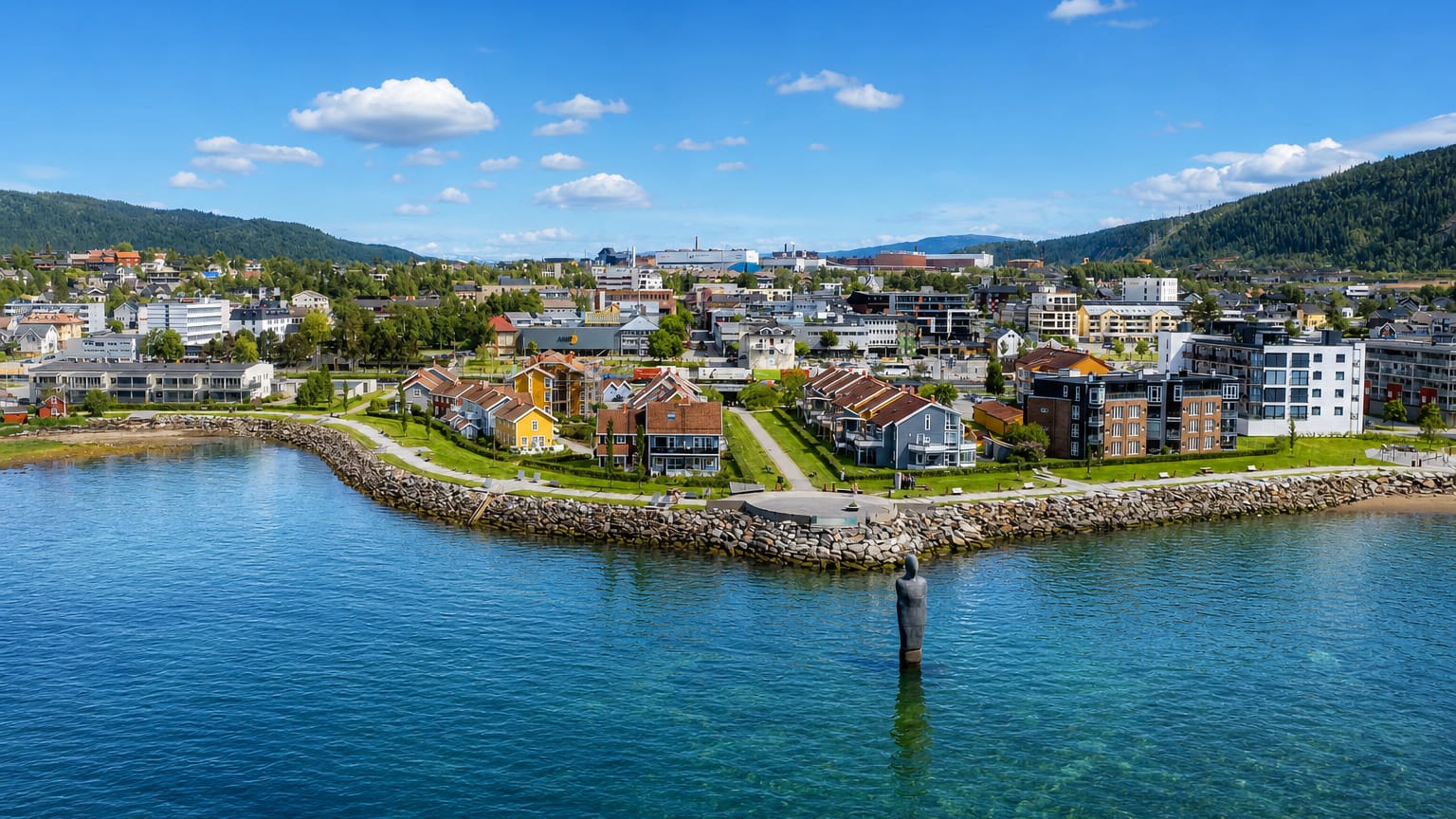 Mo i Rana waterfront with the Havmannen granite sculpture standing in the Ranfjord below the town and forested hills