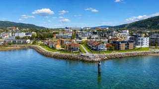 Mo i Rana waterfront with the Havmannen granite sculpture standing in the Ranfjord below the town and forested hills