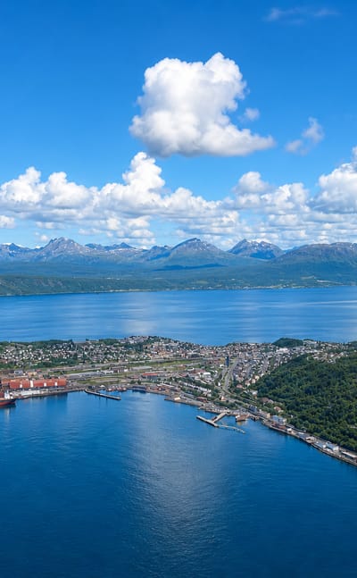 Aerial view of Narvik, Norway, its iron-ore harbour and peninsula reaching into the fjord below snow-flecked mountains.