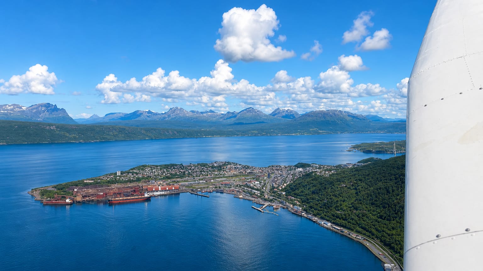 Aerial view of Narvik, Norway, its iron-ore harbour and peninsula reaching into the fjord below snow-flecked mountains.