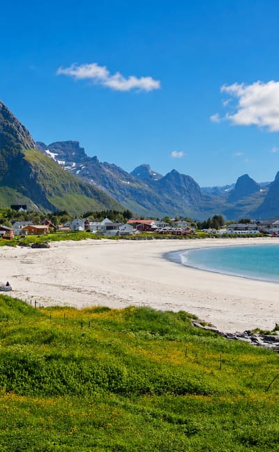 White-sand beach and turquoise bay at Ramberg backed by dramatic Lofoten mountains, Norway