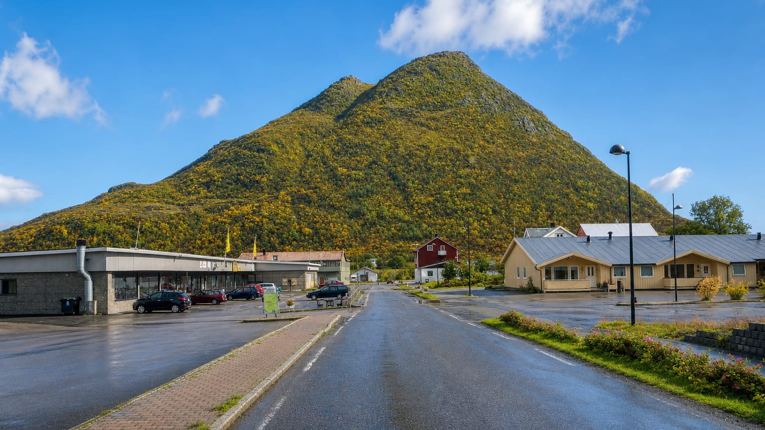 Wet main street of Straume, Norway, with a shop and a distinctive pyramid-shaped hill behind