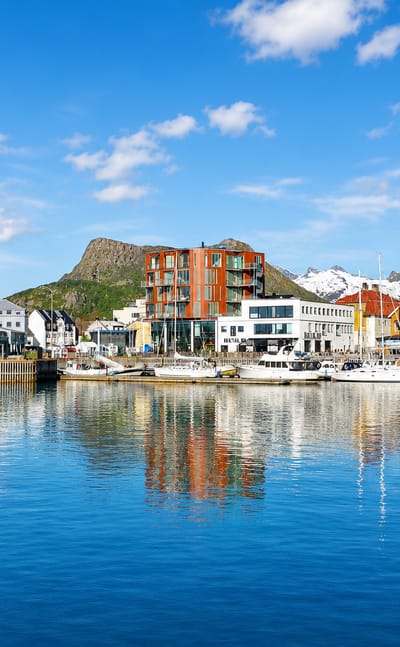 Colorful waterfront buildings and moored boats at Svolvaer harbour below the Lofoten mountains, Norway
