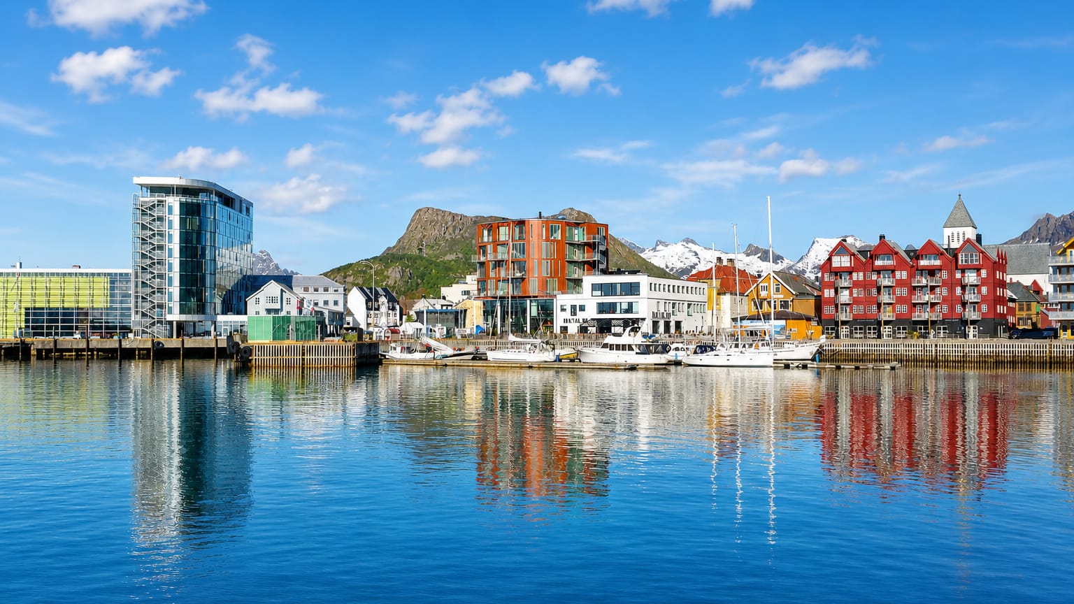 Colorful waterfront buildings and moored boats at Svolvaer harbour below the Lofoten mountains, Norway