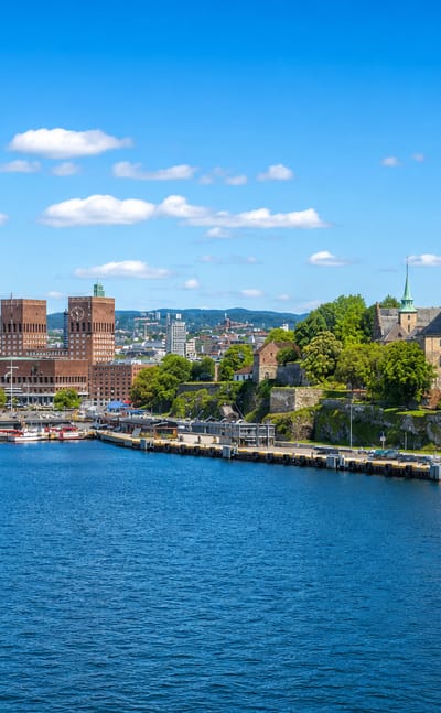 Oslo waterfront with the twin-towered City Hall and Akershus Fortress along the blue Oslofjord