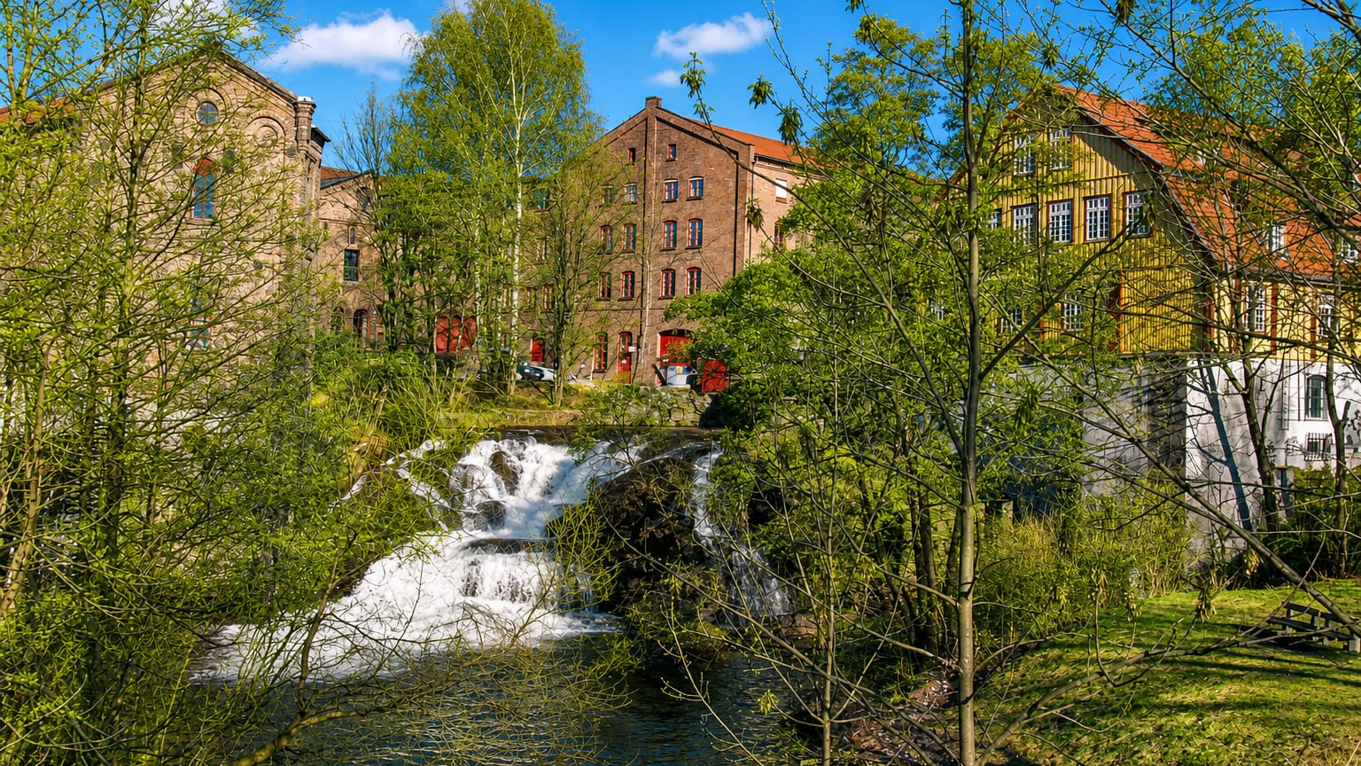 Waterfall on the Akerselva river framed by historic red-brick industrial mill buildings in Sagene, Oslo.
