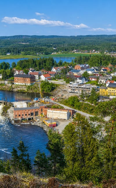 Elevated view of Ørje with its river dam, colourful timber houses and lake amid Østfold's forests.
