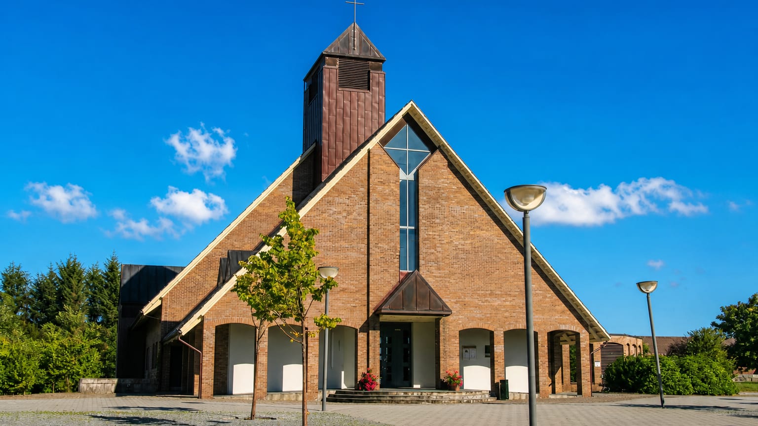 Modern brick church with a wooden bell tower and paved plaza at Aksdal under a clear blue sky