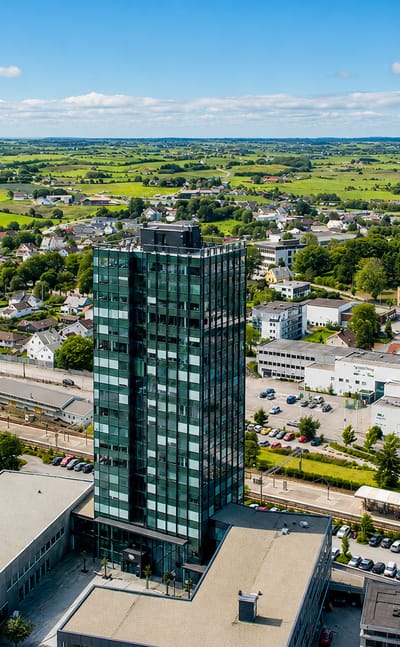 Aerial view of Bryne, Norway, with its dark glass high-rise tower rising above low town buildings and farmland