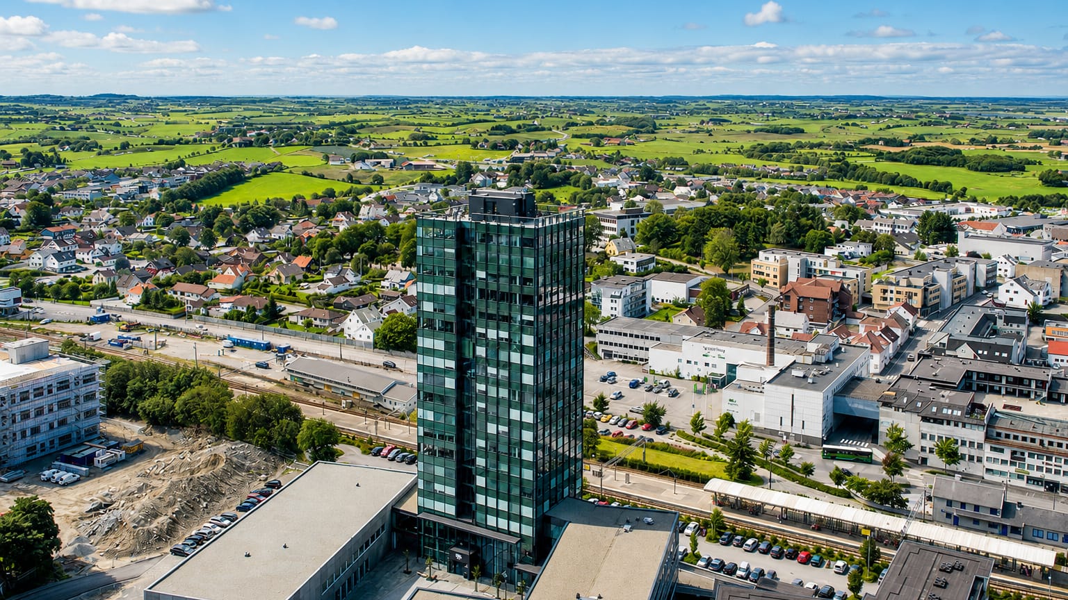 Aerial view of Bryne, Norway, with its dark glass high-rise tower rising above low town buildings and farmland