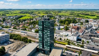 Aerial view of Bryne, Norway, with its dark glass high-rise tower rising above low town buildings and farmland