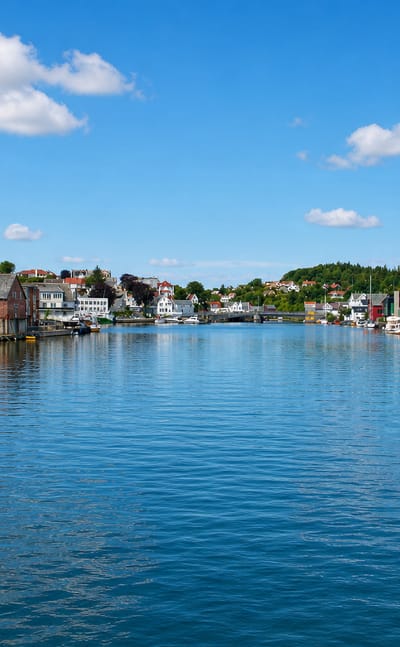 Kopervik harbour channel in Norway lined with white and red timber houses reflected in calm water
