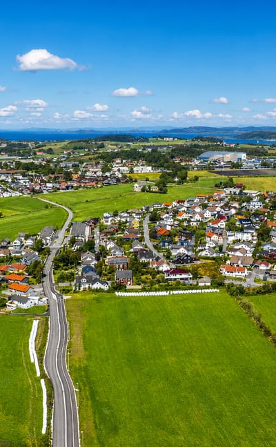 Aerial view of Randaberg's houses among green farmland by the coast, Rogaland, Norway.
