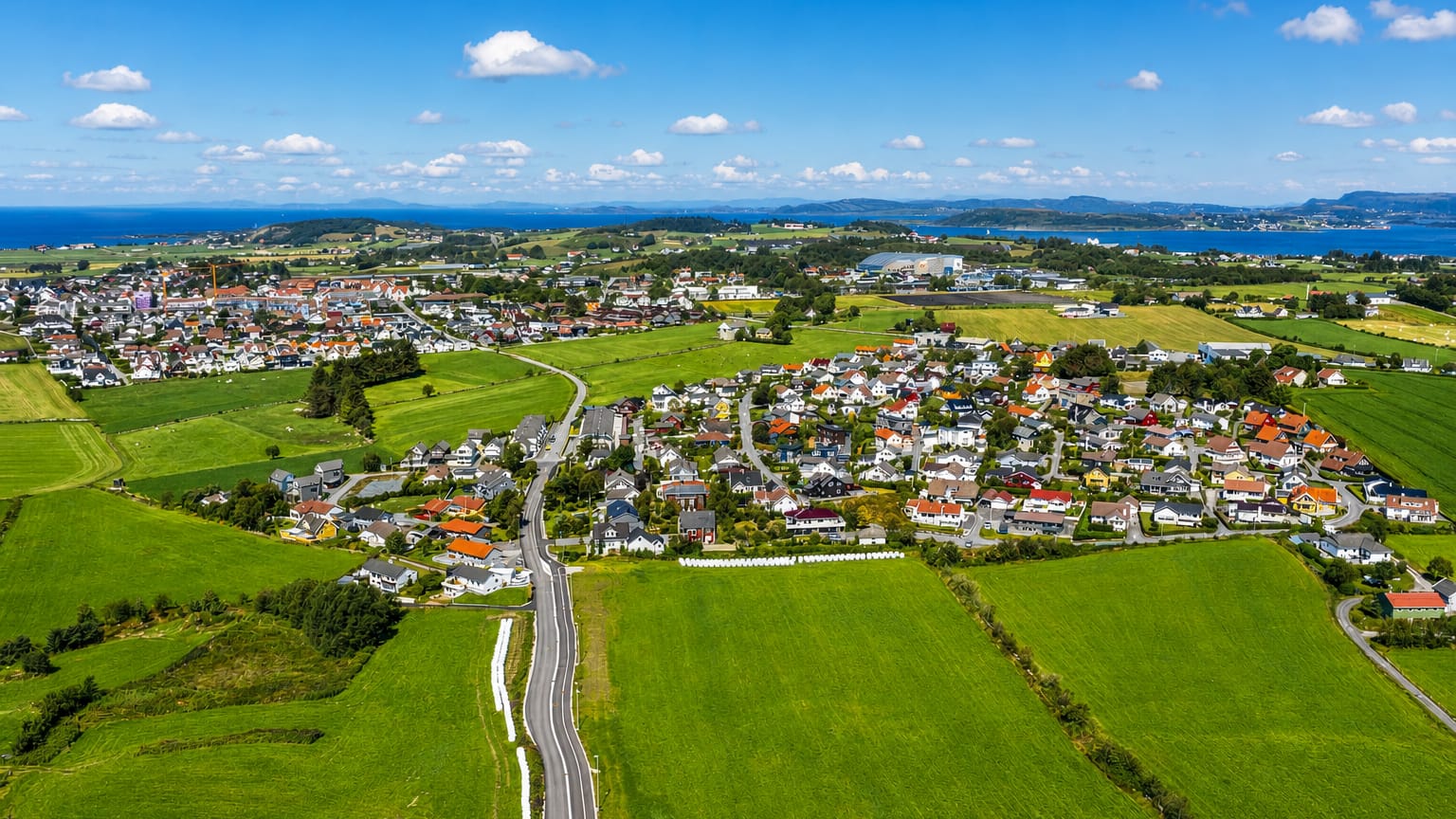 Aerial view of Randaberg's houses among green farmland by the coast, Rogaland, Norway.