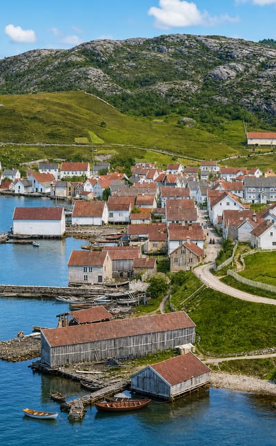 The white wooden houses of Sand, Norway, clustered around a stone harbour beside the fjord below green hills and rocky peaks.