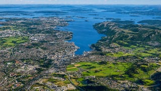 Aerial view of Stavanger spreading along the fjord amid green islands and blue water under scattered clouds
